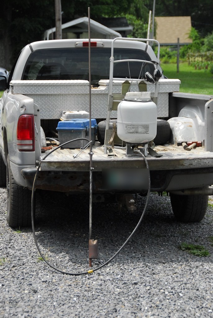Propane flame weeder wand and tank set up on a gravel drive